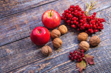 Kırmızı kartopu elma, fındık ve ahşap arka plan üzerinde sonbahar yaprakları