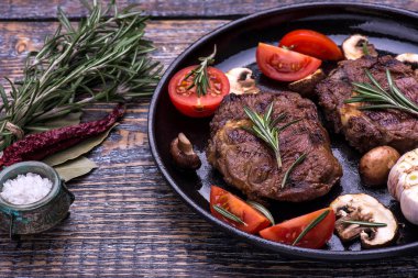 Otlar ve biberiye, taze, lezzetli, sulu bir ahşap masa arka planda ile sığır eti biftek. 