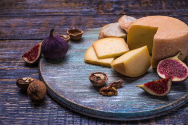 Ürünler - peynir, zeytin, üzüm, fındık ve ayarla incir ahşap bir tahta üzerinde arka plan