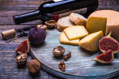 Kırmızı şarap bir şişe, mantar, şişe vida ve ürünler - peynir, üzüm, fındık, zeytin, incir ahşap bir gemide bir dizi arka plan