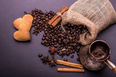 Kahve fincanı, kahve çekirdekleri ve bisküvi, siyah arka plan üzerinde kalp şeklinde kurabiye