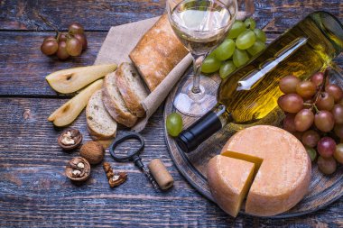 Beyaz şarap bir şişe, mantar, şişe vida ve ürünler - peynir, üzüm, fındık, zeytin, incir ahşap bir gemide bir dizi arka plan