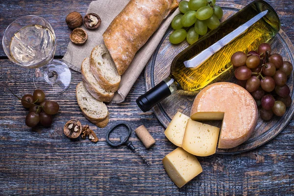 Белое вино в боттле, пробка, винт и набор продуктов - сыр, виноград, орехи, оливки, инжир на деревянной доске, фон — стоковое фото