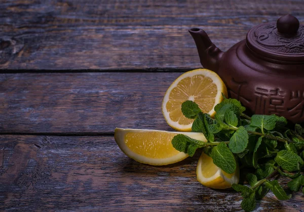 Grüner Tee in der Teekanne mit Zitronen- und Minzblättern auf Holzgrund — Stockfoto