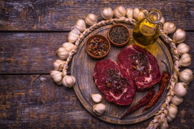 Ham sığır eti biftek, tuz, biber, sarımsak, biberiye, zeytin yağı, ahşap masa, arka plan mantar.