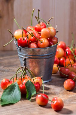 Güzel kokulu ve Olgun Kiraz ahşap arka plan üzerine bir kova içinde. Seçici odak