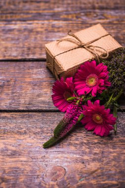 Mevcut kutusu ve ahşap arka plan üzerinde kırmızı çiçekler