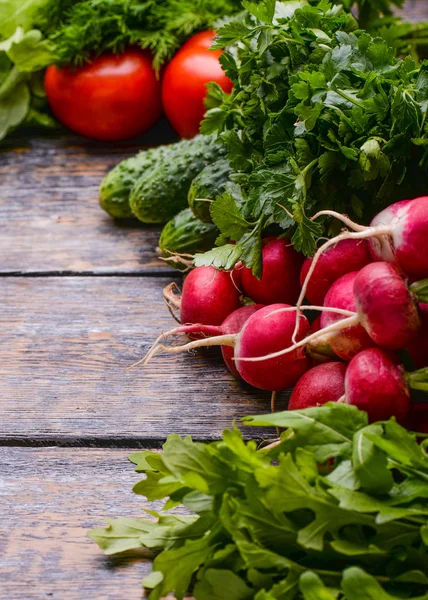 Збір врожаю Овочі: салат, помідори, огірки, петрушка, цибуля, рукола в кошику на дерев'яному тлі — стокове фото