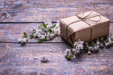 Çiçek açması beyaz bir tablo, bir hediye, hediye kutusu, ahşap arka plan üzerinde kiraz Şubesi