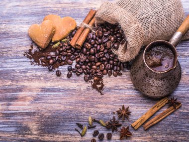 Kahve fincanı, kahve çekirdekleri ve bisküvi, ahşap arka plan üzerinde kalp şeklinde kurabiye