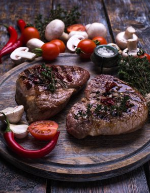 Izgara dana biftek, tuz, biber, sarımsak, biberiye, zeytinyağı ahşap gemide, arka plan.