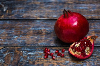 Lal kırmızı, olgun, sulu, bütün ve bir nar, tahıl, tohum ahşap arka plan üzerinde yarısı