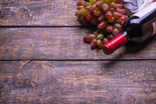 Red wine bottle,  set of products -  grapes on a wooden board, background