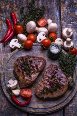 Ham sığır eti, ızgara biftek, tuz, acı biber, sarımsak, domates, kekik, biberiye ahşap bir masa, arka plan üzerinde.
