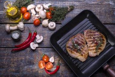 Ham sığır eti, ızgara biftek, tuz, acı biber, sarımsak, domates, kekik, biberiye ahşap bir masa, arka plan üzerinde.