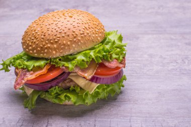 Zanaat sığır eti burger taze sebze, domates, peynir, omion, ahşap masa siyah arka plan üzerine izole üzerinde yeşil salata ile.