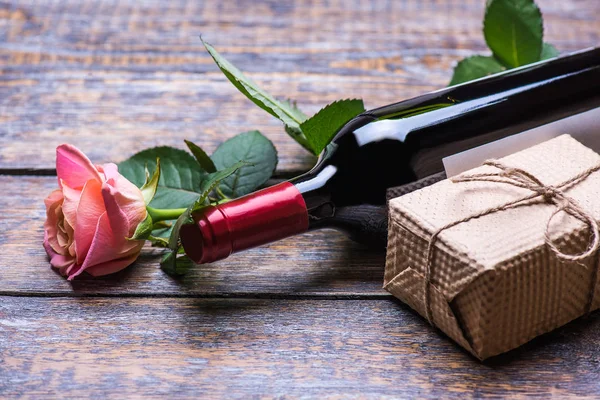 Spring flowers rose, bottle of red wine, present box, gift on dark vintage wooden background