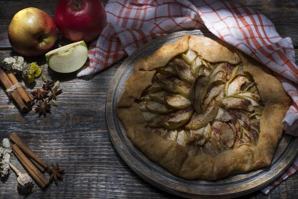 Zelfgemaakte appeltaart met poedersuiker, specerijen: kaneel, kardemom, anijs, vanille, appels, geserveerd met een textiel-handdoek op een houten bord, achtergrond — Stockfoto