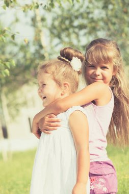 Parkta oynarken mutlu iki kız kardeş.