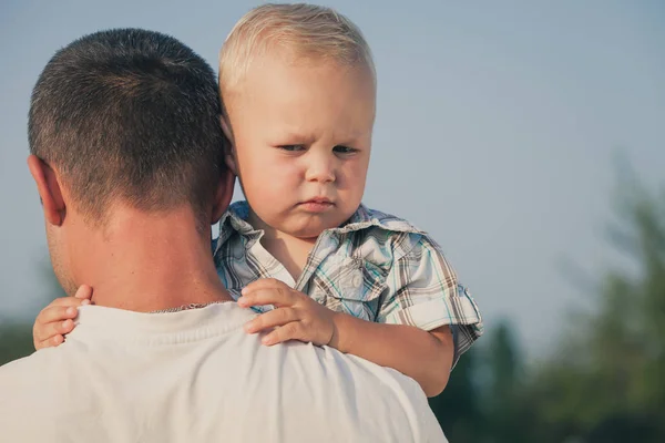 Smutny syn przytulanie jego tata w parku w czasie dnia — Zdjęcie stockowe