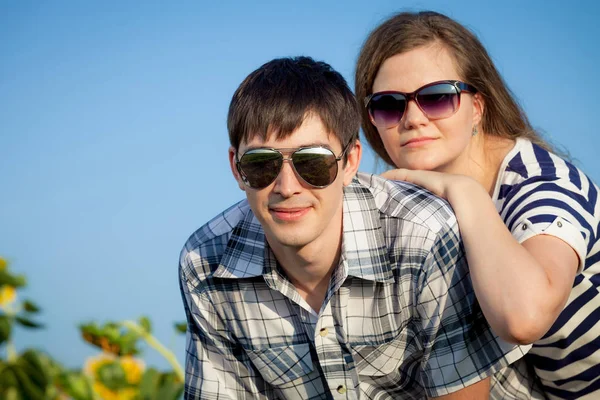 Portrait of young couple standing with sunflowers in a field. — Stock Photo, Image