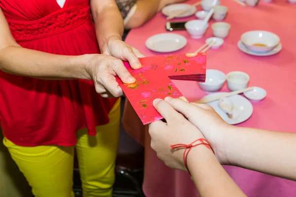 Chinese person giving red packet with Good Luck Chinese word