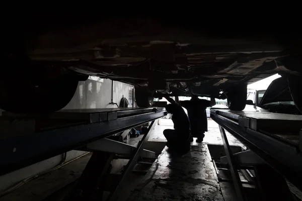 Silhouette of mechanics reparing car at small workshop garage — Stock Photo, Image