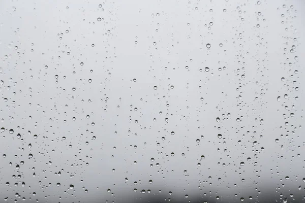Rain water droplets on glass window with gloomy sky