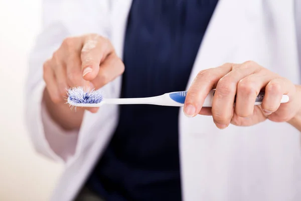 Dentist pointing at old worn out toothbrush bristle — Stock Photo, Image