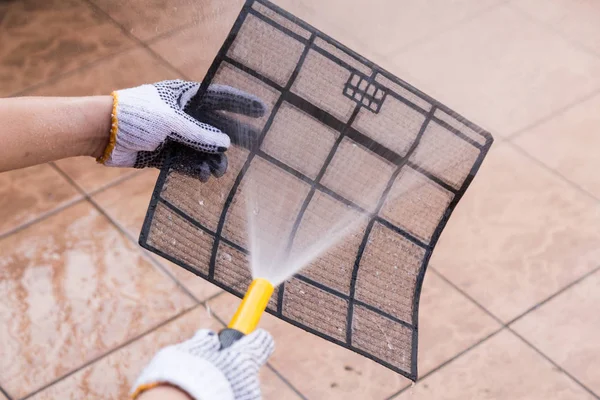 Person sprüht Wasser auf Klimaanlage Filter, um Staub zu reinigen — Stockfoto