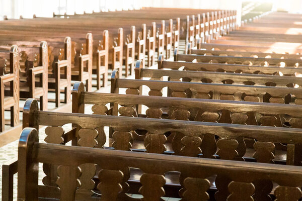 Rows of empty pew benches inside chapel church