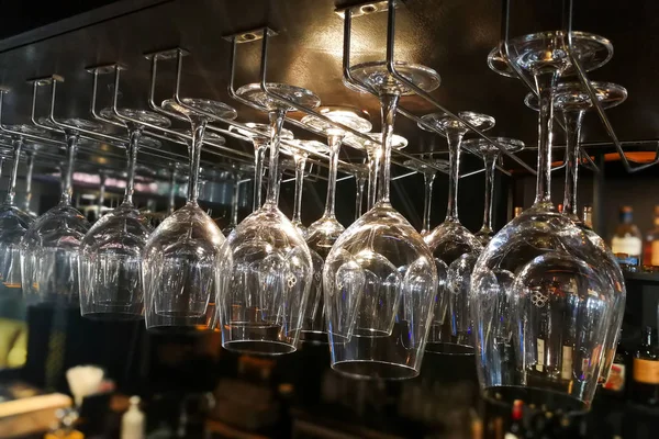 Empty wine glasses hanging on rack in bar