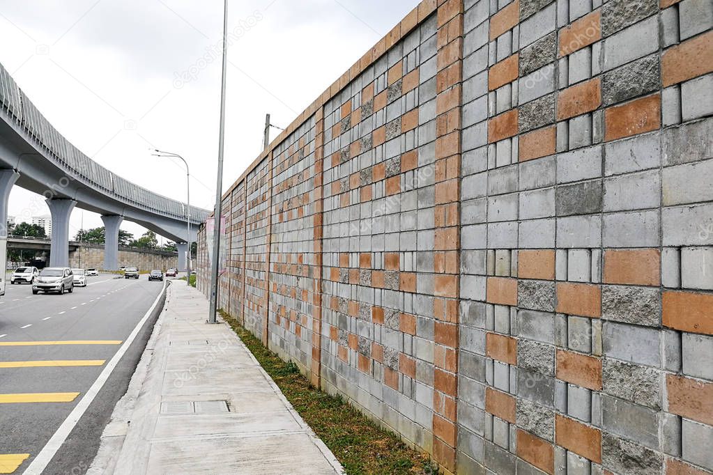 Concrete sound barrier wall next to busy highway rail track