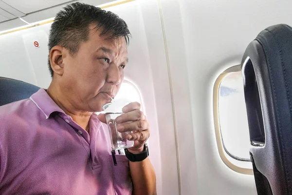 Лицо, пьющее воду в самолете, долгий полет для увлажнения — стоковое фото