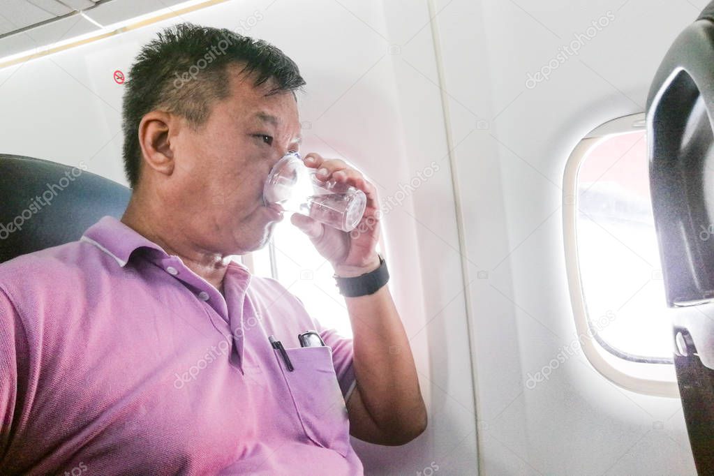 Person drinking water in airplane long haul flight to hydrate  