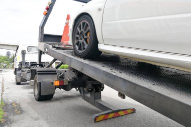 Car towed onto flatbed tow truck with hook and chain clipart