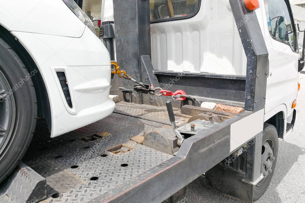 Car towed onto flatbed tow truck with hook and chain