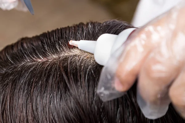 Hair dresser applying chemical hair color dye onto hair roots — Stock Photo, Image