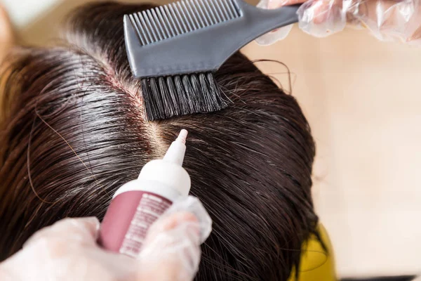 Hair dresser applying chemical hair color dye onto hair roots — Stock Photo, Image