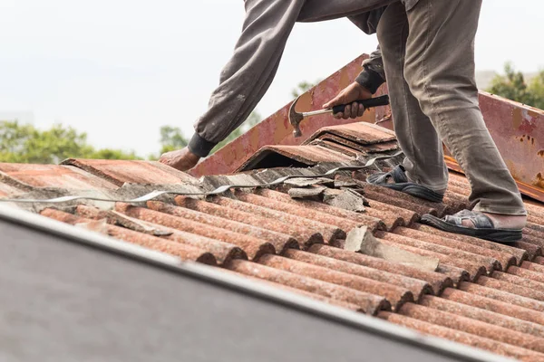 Asian worker replacing roof tiles of old residential building