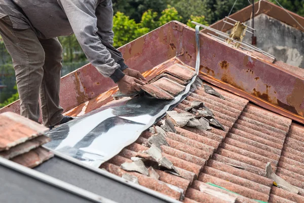 Trabajador asiático reemplazando tejas de edificio residencial antiguo — Foto de Stock