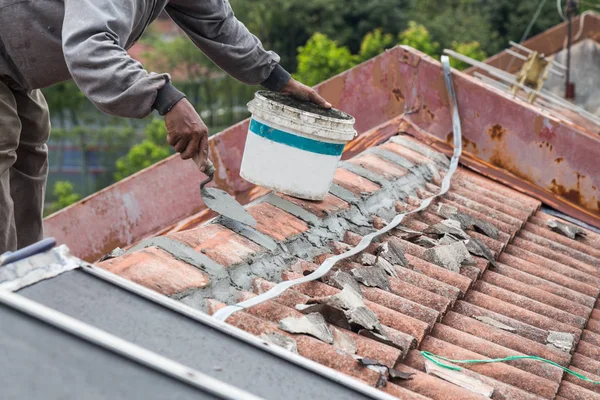 Trabajador asiático asegurar tejas con cemento en el edificio viejo — Foto de Stock