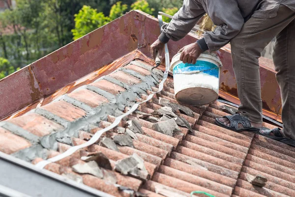 Asiatische Arbeiter sichern Dachziegel mit Zement auf Altbau — Stockfoto