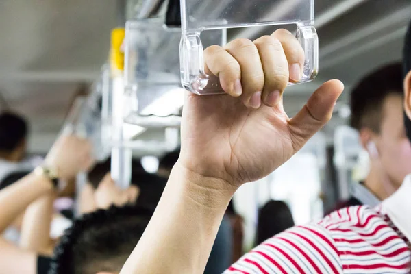 Passengers holding the hand rail on crowded public transports.