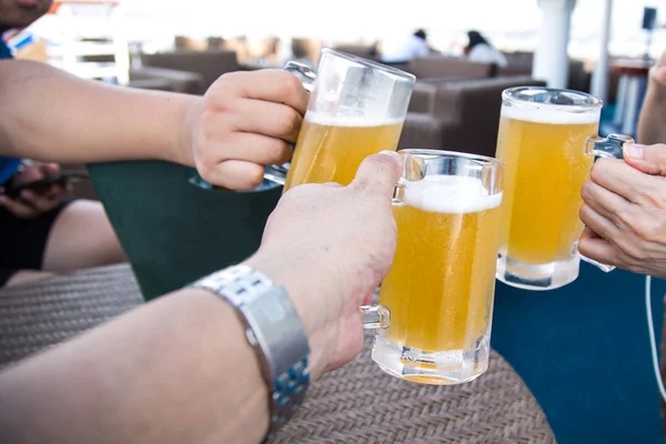 Três pessoas batendo copos de cerveja para brindar em celebração — Fotografia de Stock