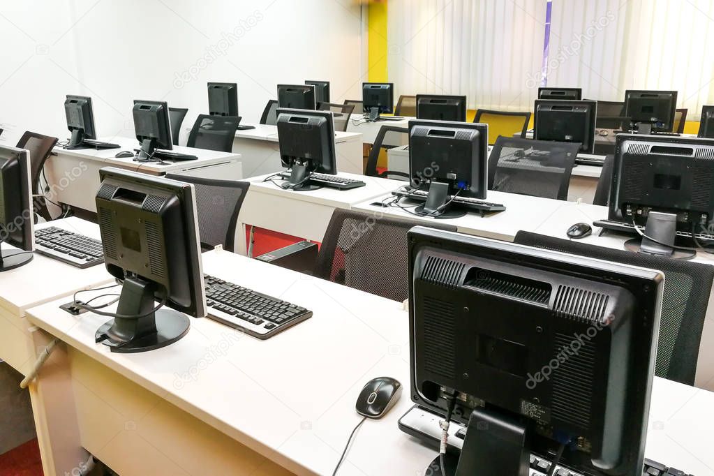 Empty computer classroom with monitors on top of table