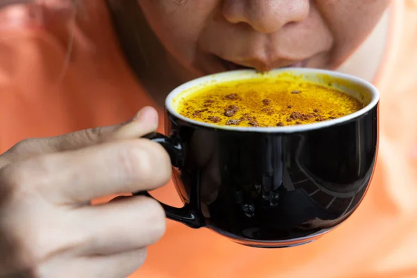 Persona che si gode una tazza di curcuma caffè nero in caffè — Foto Stock