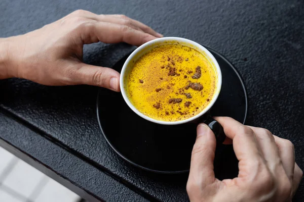 Orang menikmati secangkir kopi kunyit hitam di kafe — Stok Foto