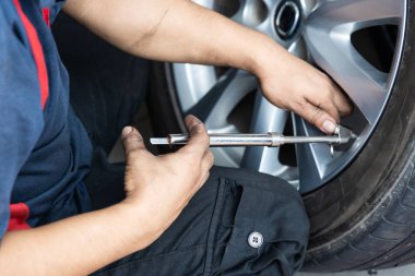 Tamirci lastik basıncını lastik basınç göstergesi ile kontrol ediyor. 