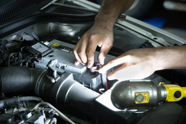 Mekaniker inspekterar och byter bilbatteri i garaget — Stockfoto